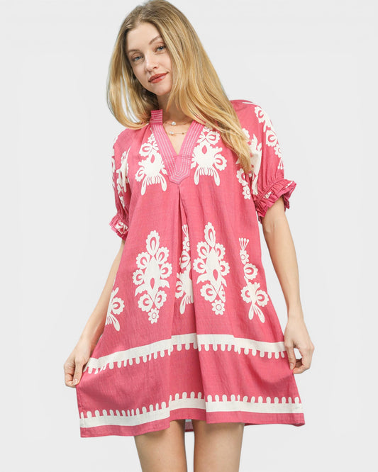 Woman wearing a pink dress with white patterns on a white background