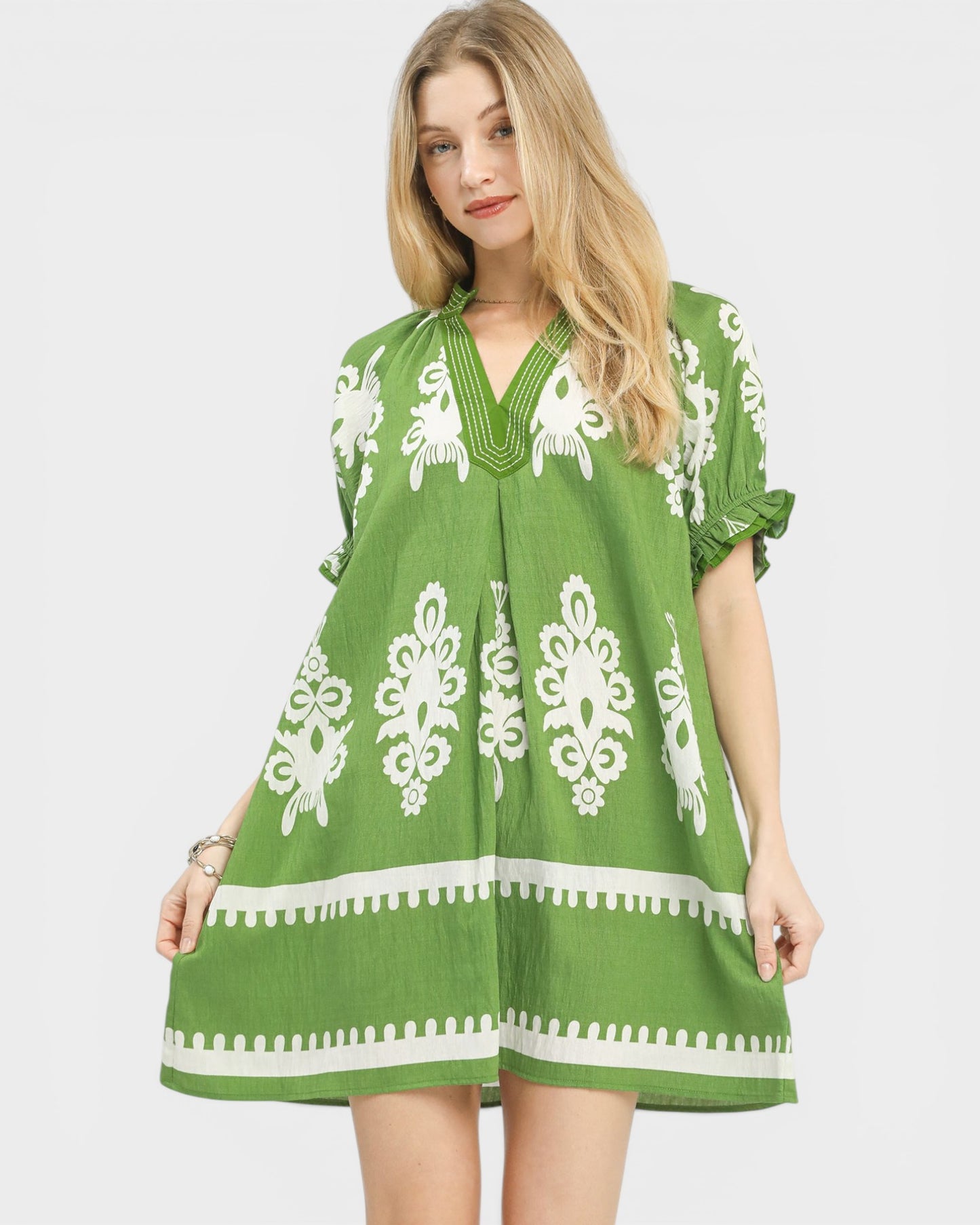 Woman wearing a green dress with white patterns on a plain background