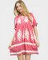 Woman wearing a pink dress with white patterns on a white background