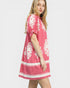 Woman wearing a pink dress with white patterns on a white background