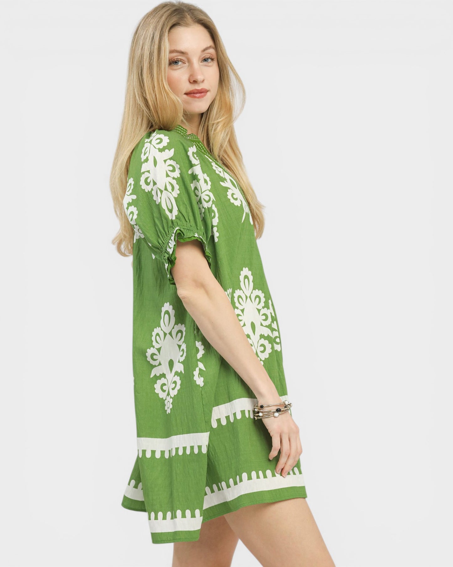Woman wearing a green dress with white patterns on a white background