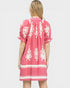 Woman wearing a pink dress with white patterns on a white background