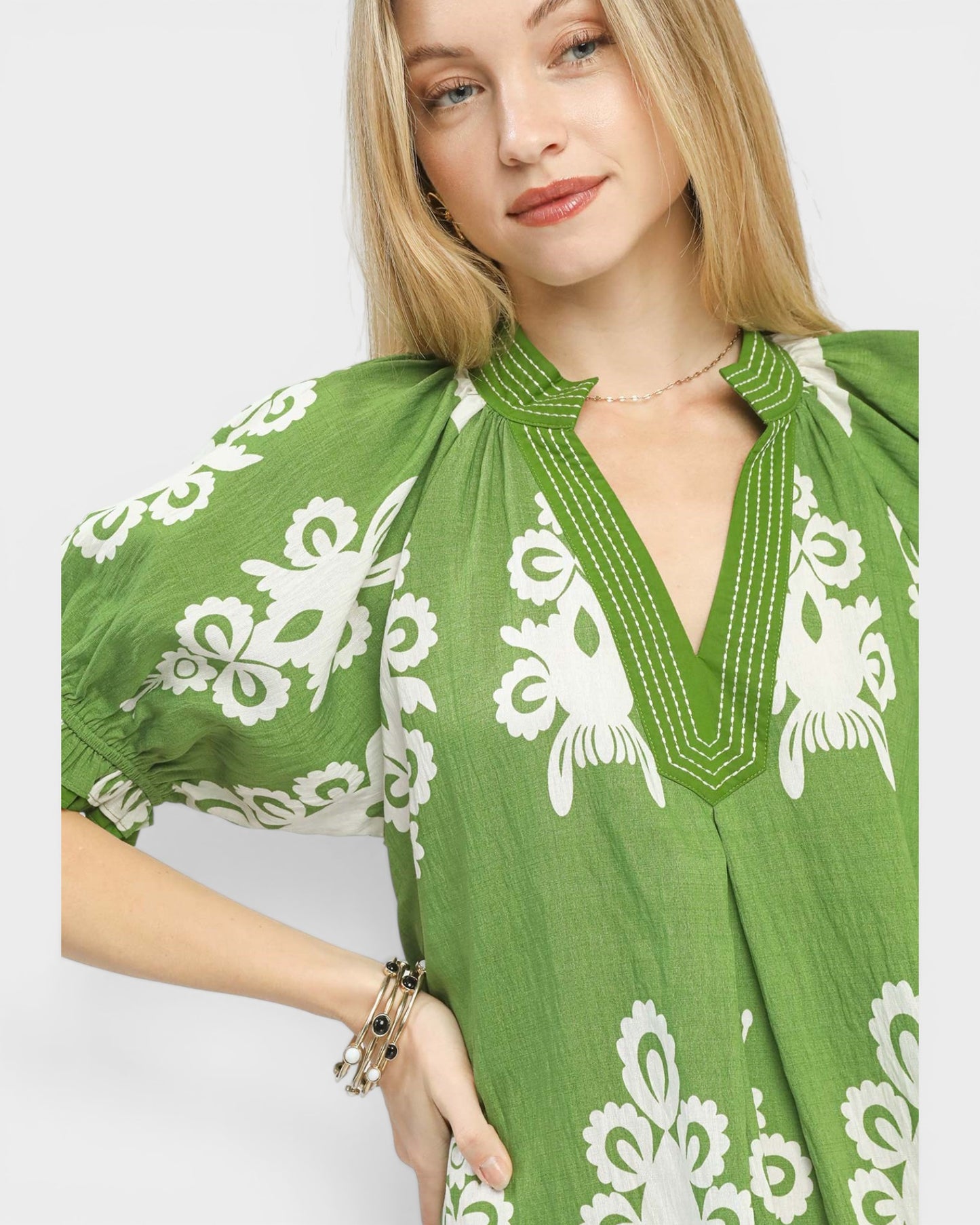 Woman wearing a green dress with white floral patterns on a plain background