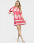 Woman wearing a pink dress with white floral patterns on a white background