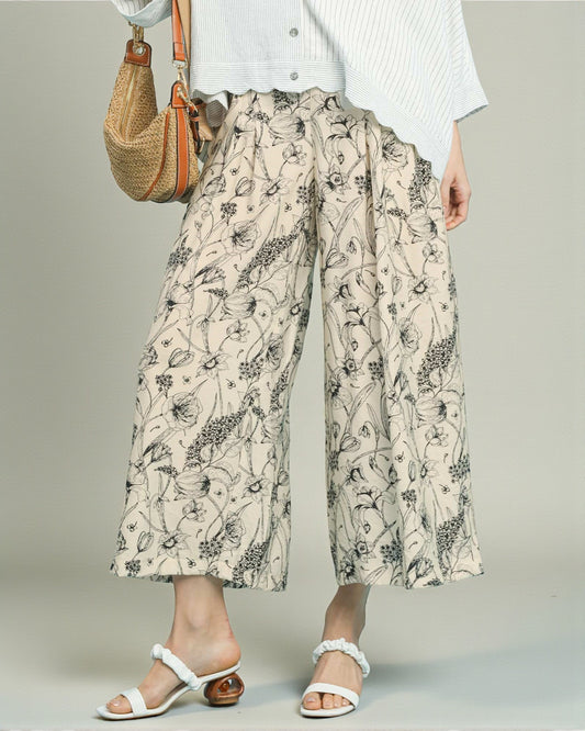 Person wearing floral-patterned wide-leg pants with a plain background