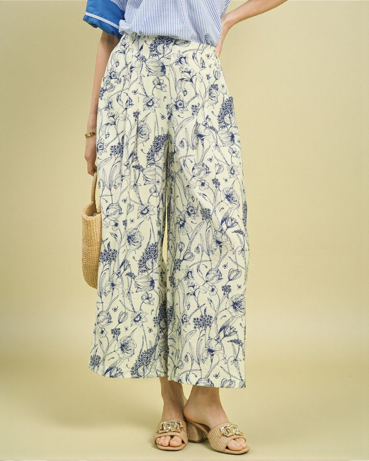 Person wearing floral wide-leg pants with a plain background