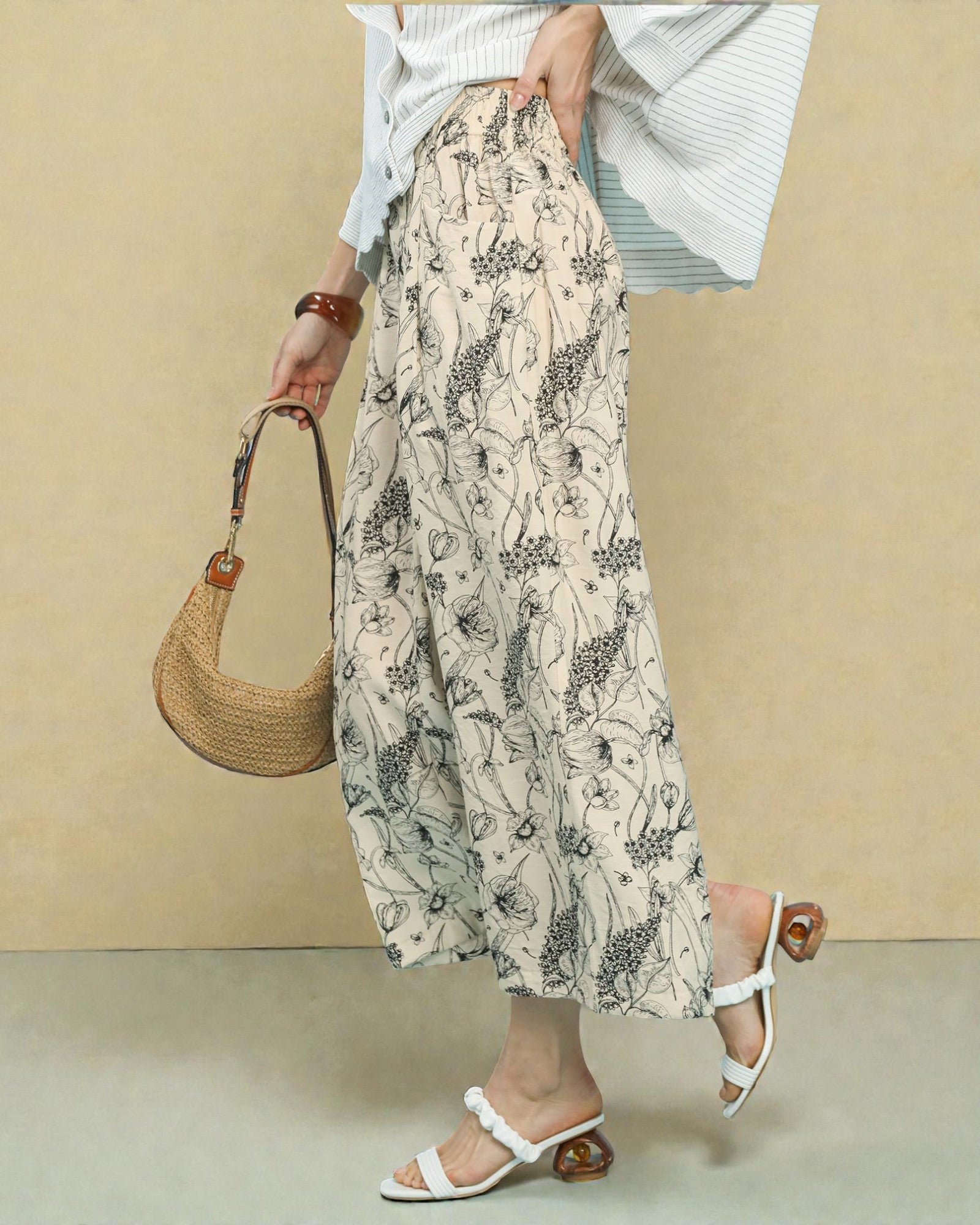 Person wearing a floral skirt and holding a woven bag against a beige background