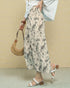 Person wearing a floral skirt and holding a woven bag against a beige background