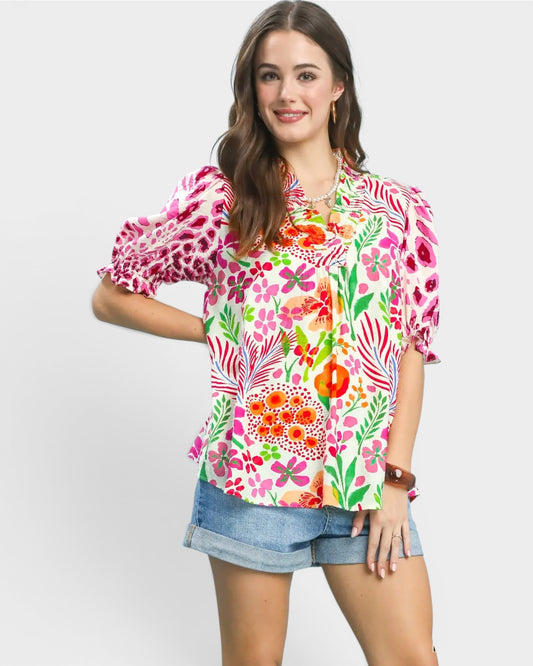 Woman wearing a colorful floral blouse with puff sleeves on a white background