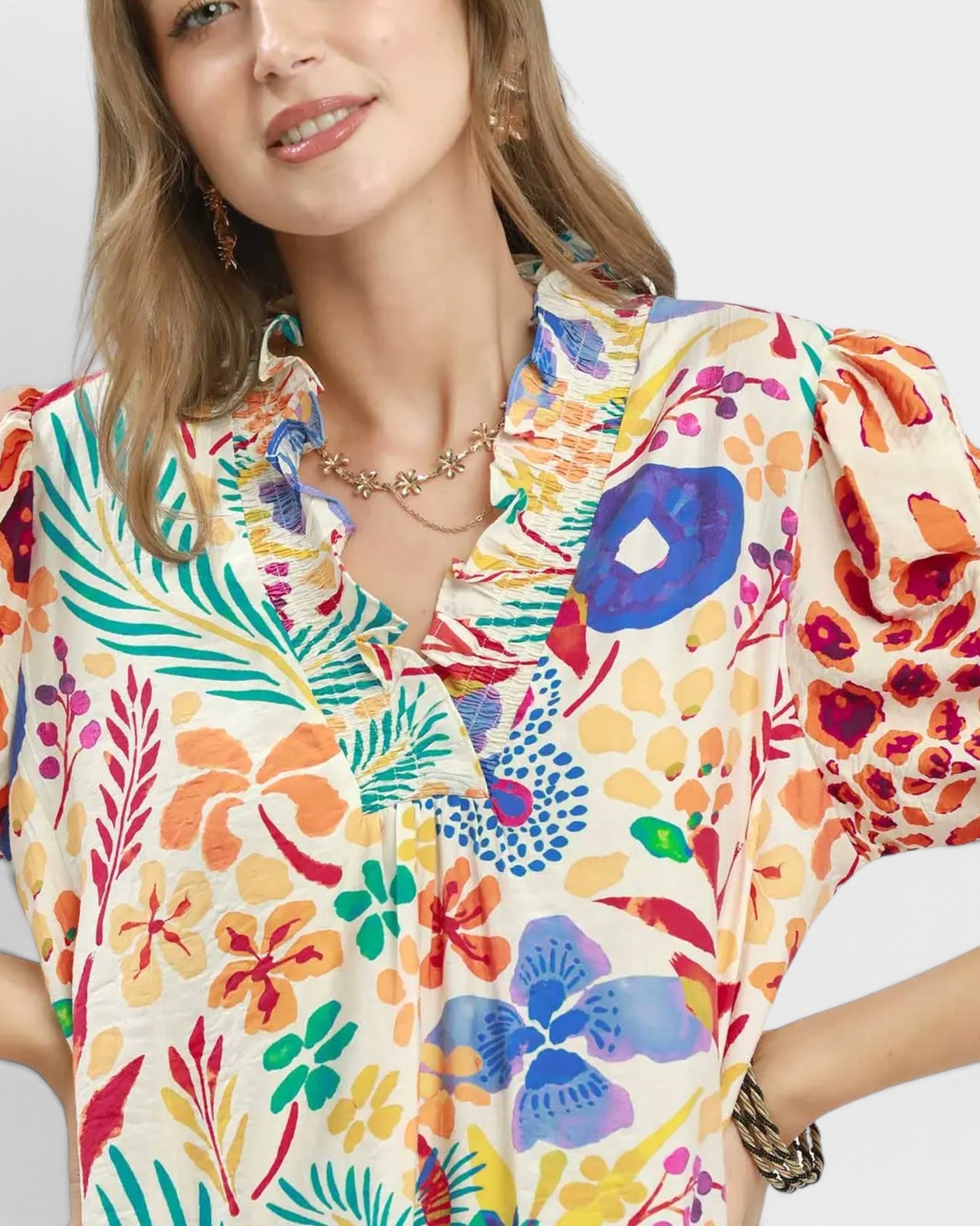 Woman wearing a colorful floral blouse against a white background