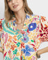 Woman wearing a colorful floral blouse against a white background