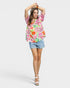 Woman wearing a colorful floral blouse and denim shorts on a white background