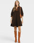 Woman wearing a brown dress with decorative trim and brown boots on a white background