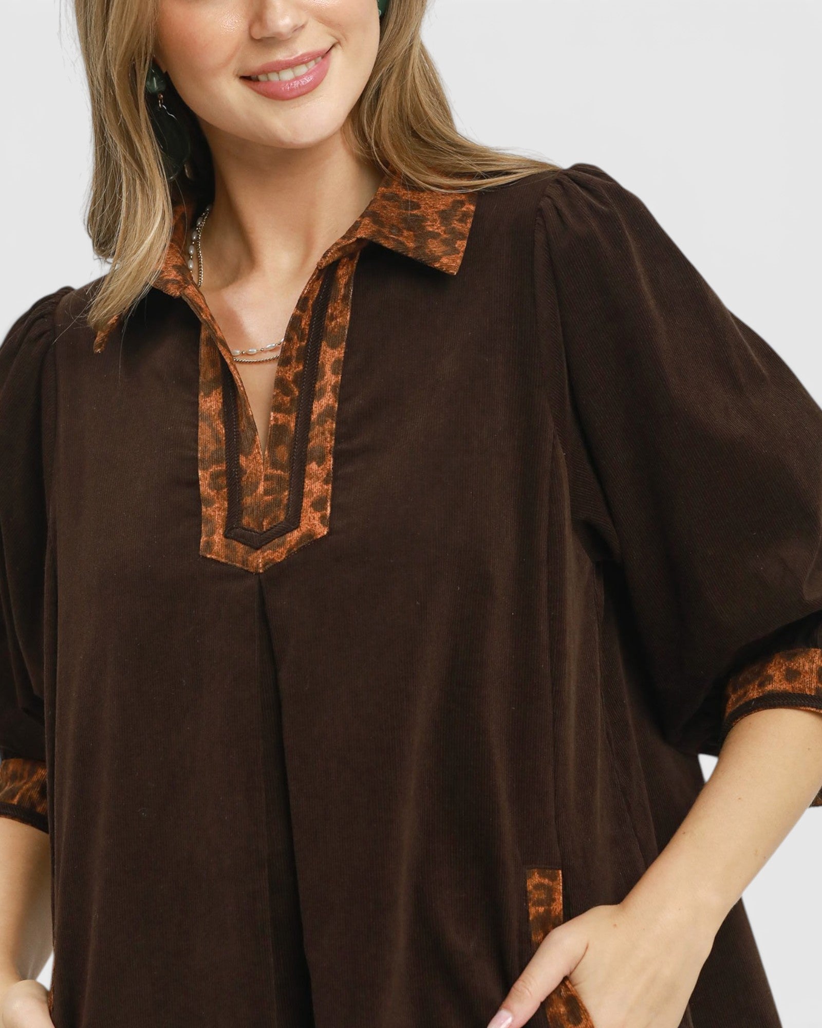 Brown blouse with decorative trim on a plain background