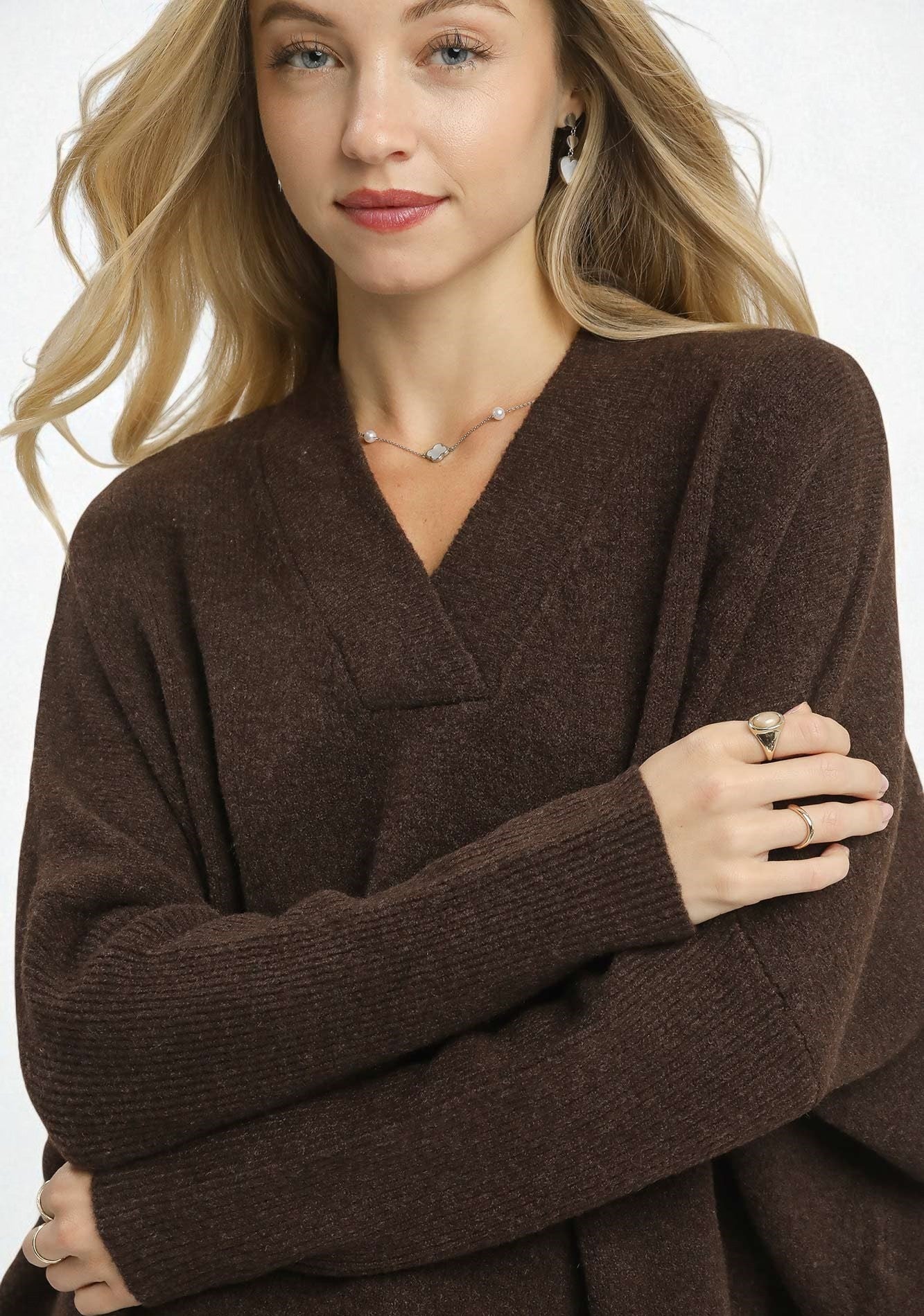 Woman wearing an espresso brown sweater with a plain background