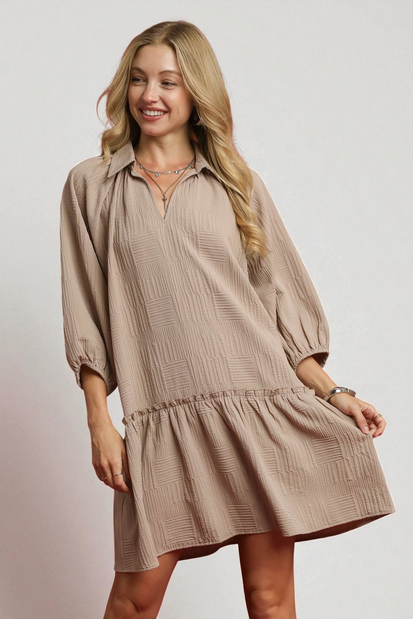 Woman wearing a beige dress on a plain background