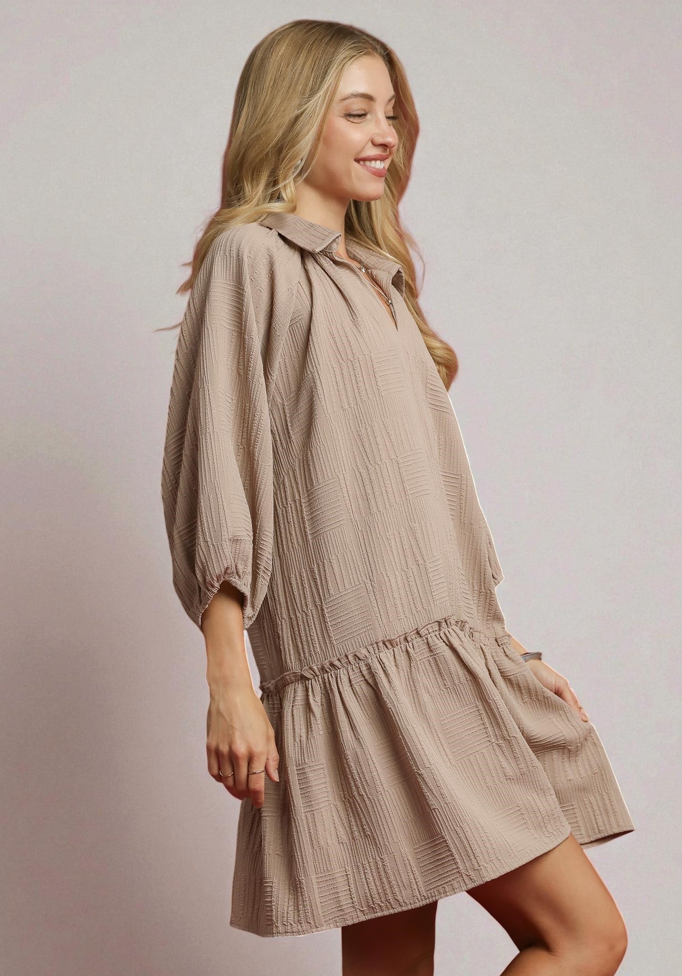 Woman wearing a beige dress against a plain background