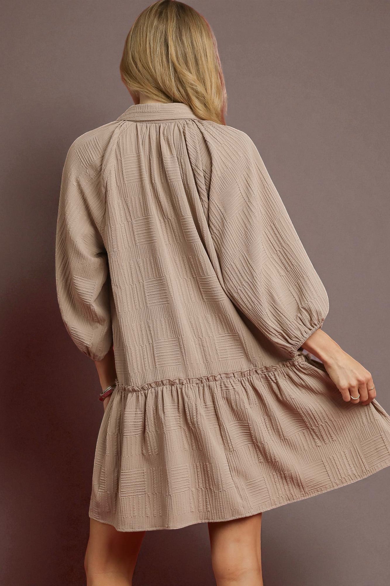 Woman wearing a beige textured dress against a brown background