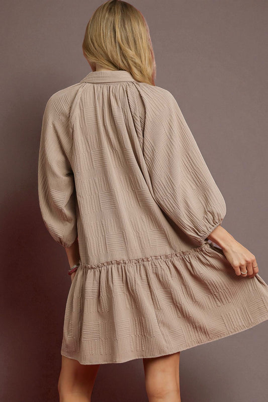 Woman wearing a beige textured dress against a brown background