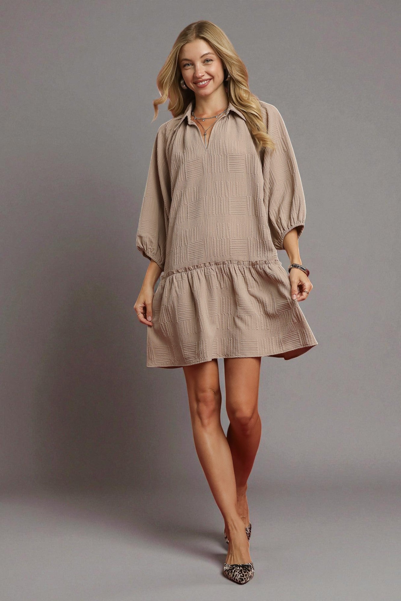 Woman wearing a beige dress against a gray background