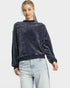 Woman wearing a dark blue velour sweater and light blue jeans on a white background
