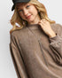 Woman wearing a brown sweater and black cap on a white background