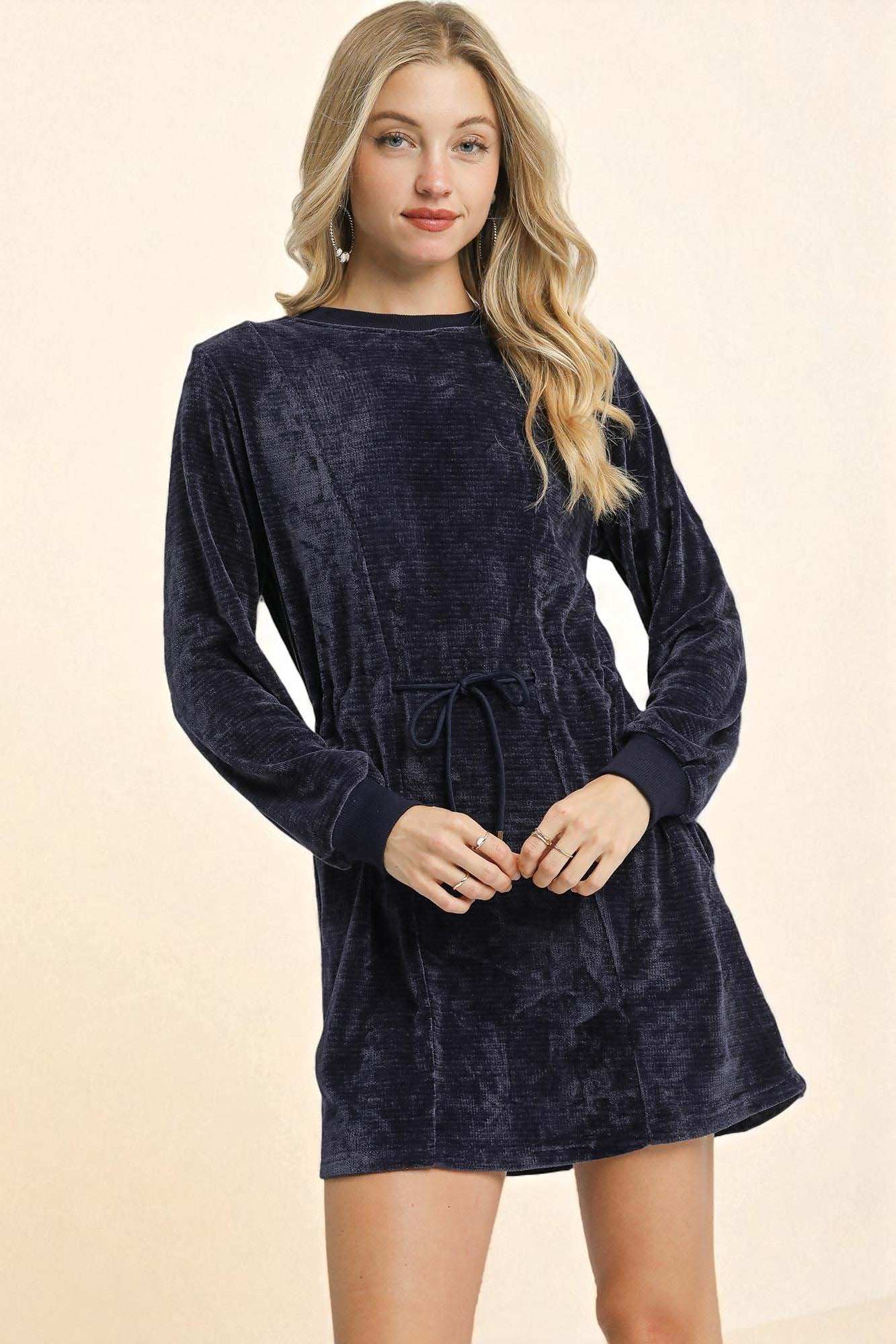 Woman wearing a navy blue velvet dress on a beige background