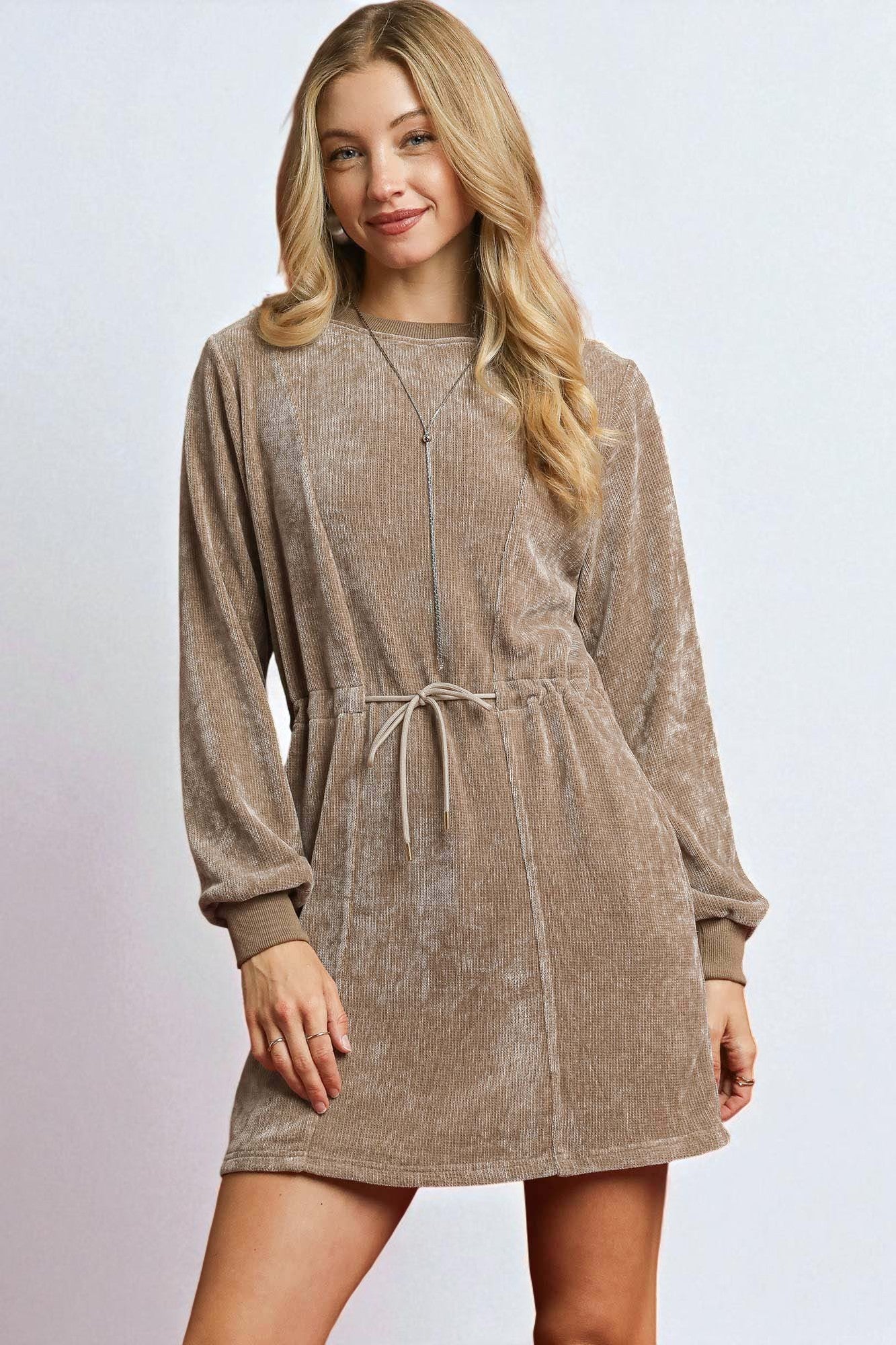 Woman wearing a brown corduroy dress with a plain background