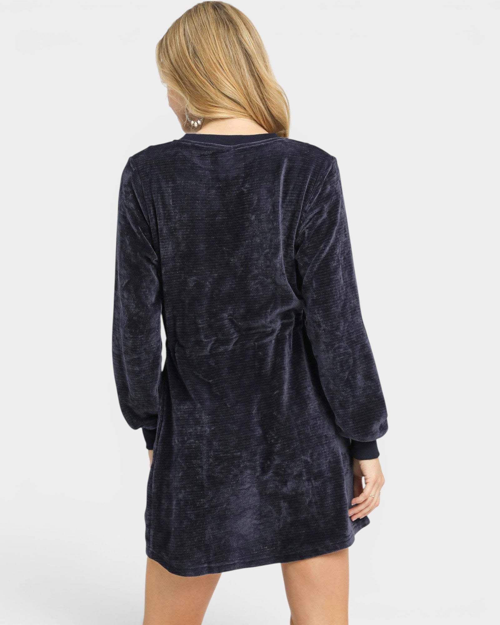 Person wearing a dark blue velour dress on a white background