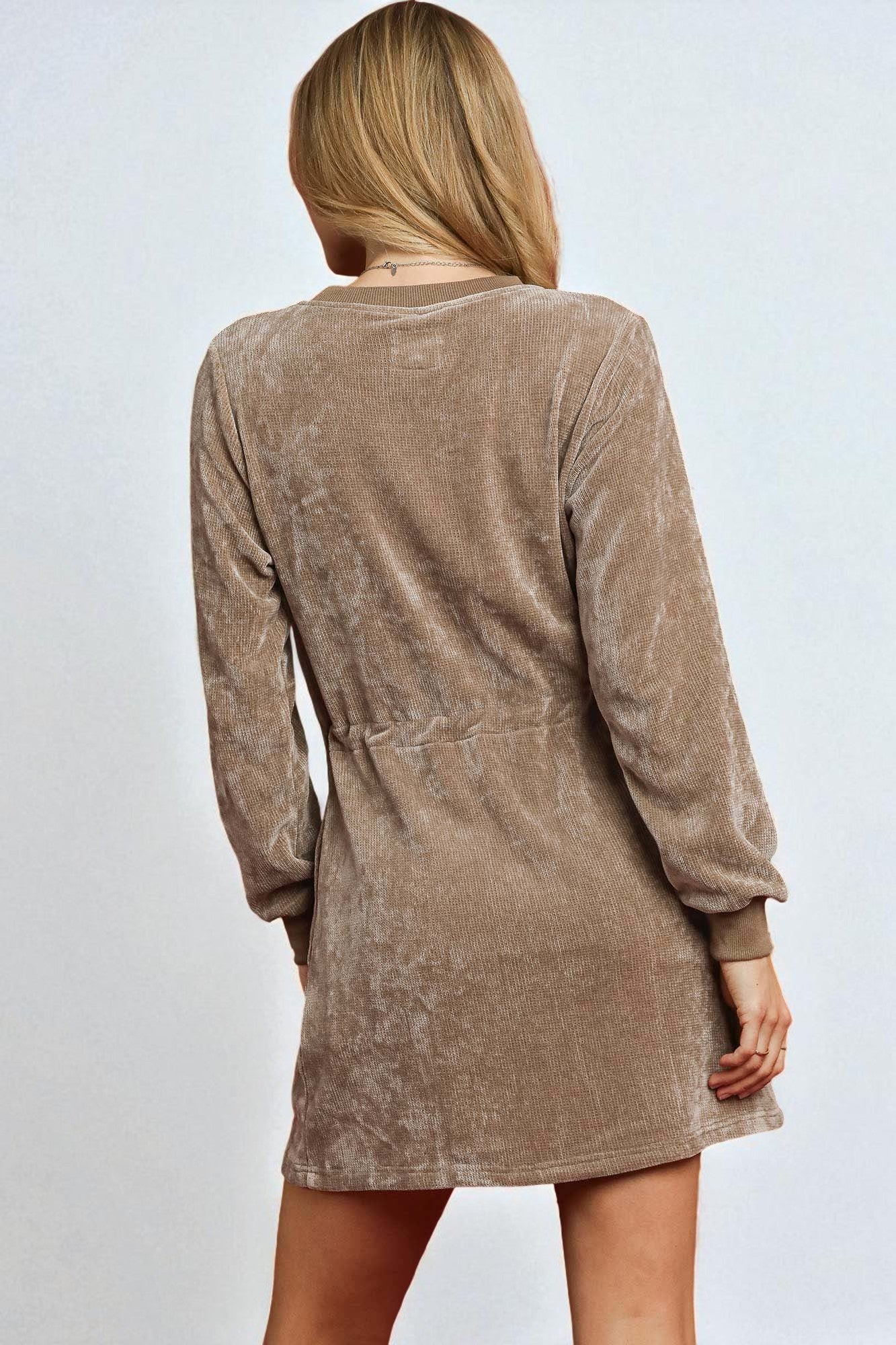 Person wearing a brown velour dress against a plain background