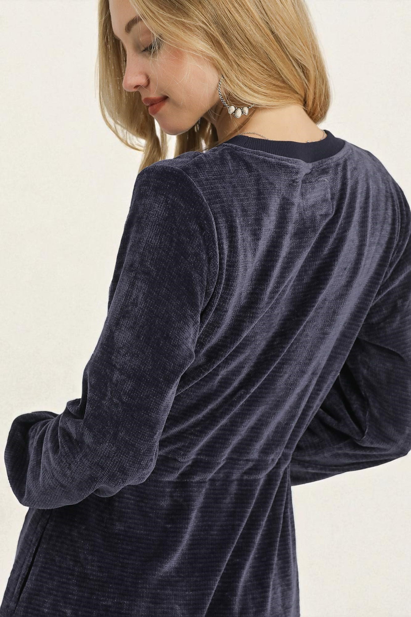 Person wearing a dark blue velour robe against a light background