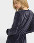 Woman wearing a dark blue velour dress against a white background