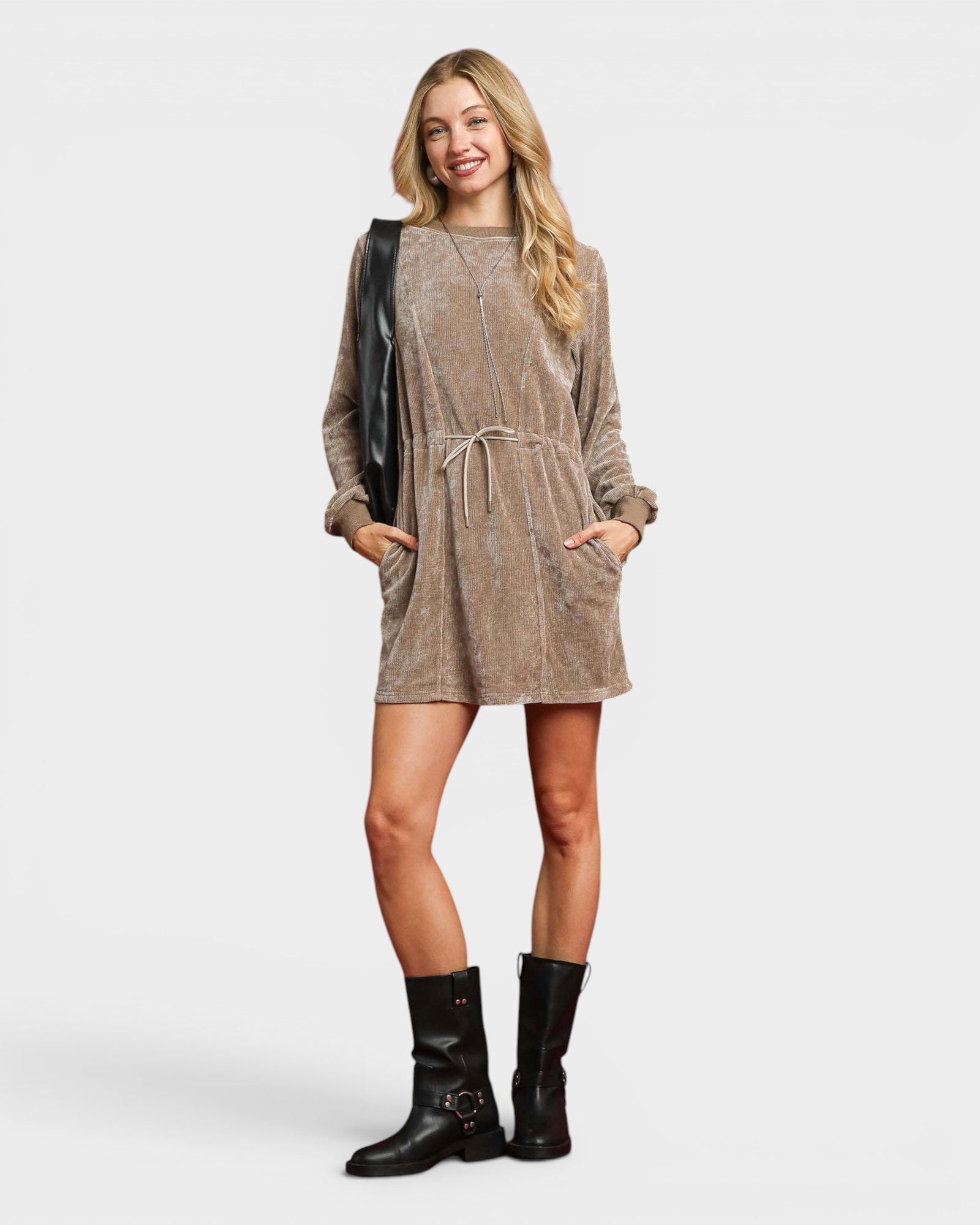 Woman wearing a brown dress with black boots on a white background