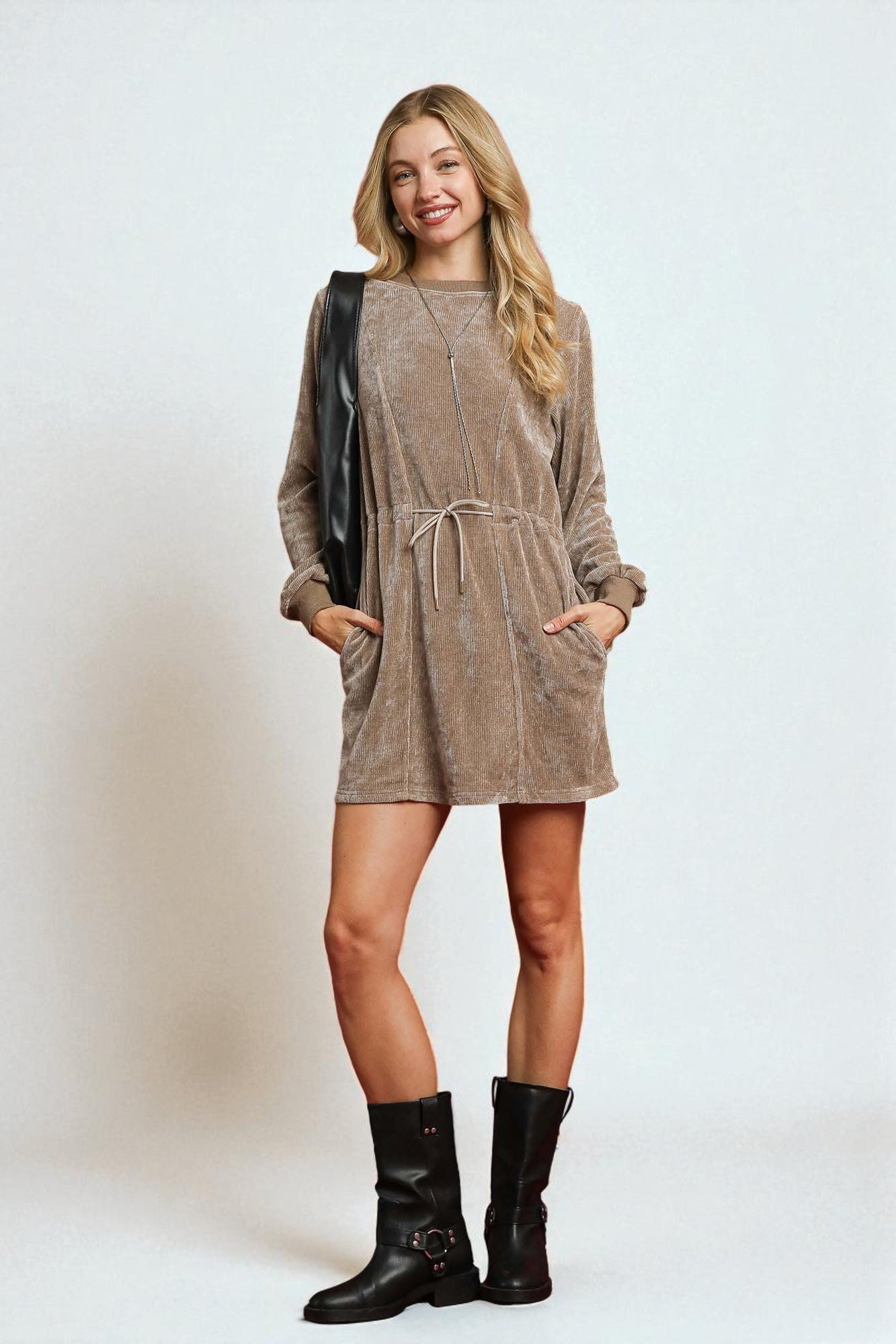 Woman wearing a brown dress and black boots on a white background