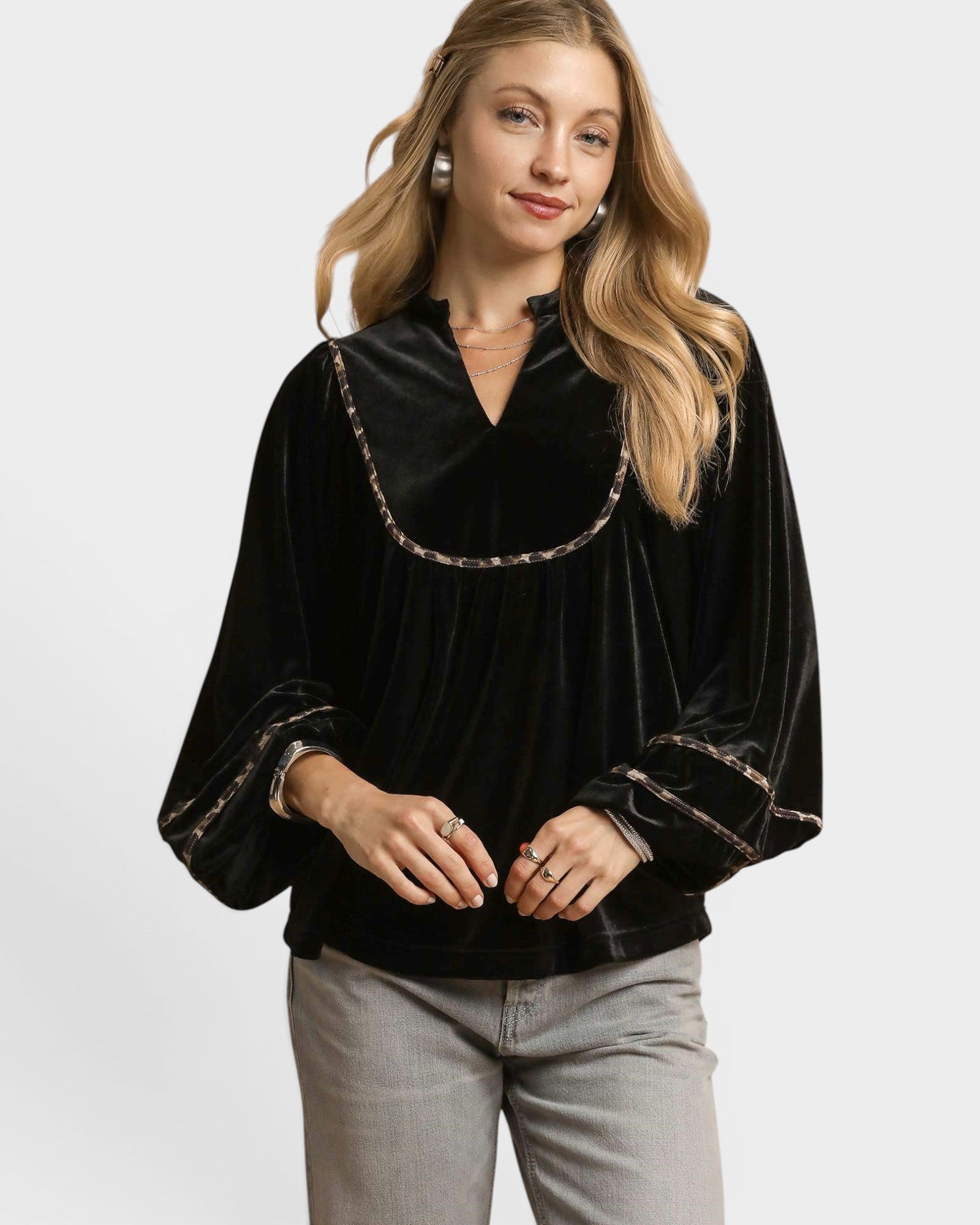 Woman wearing a black velvet blouse with gold trim on a white background