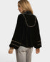 Woman wearing a black velvet blouse with gold trim on a white background