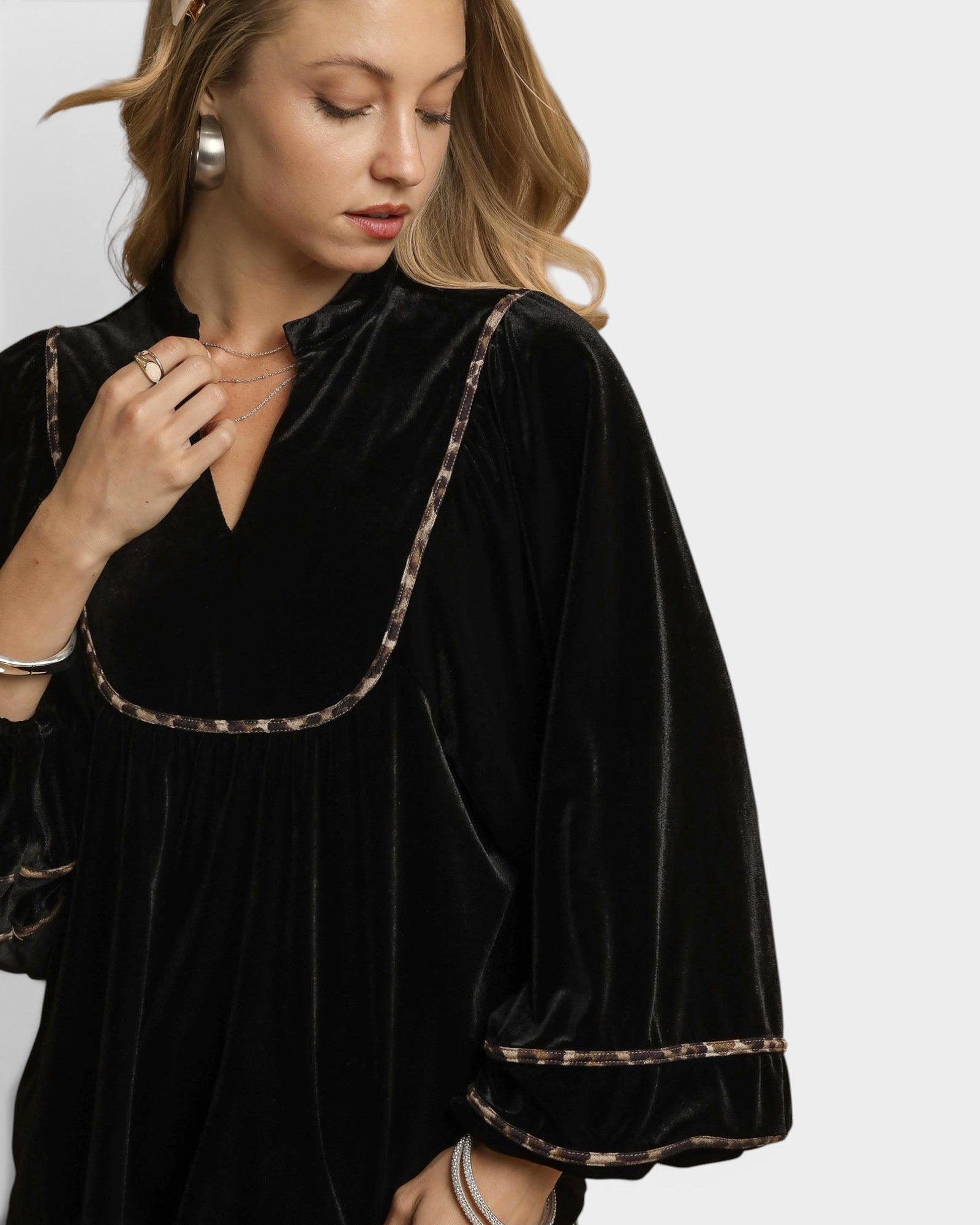 Woman wearing a black velvet dress with gold trim on a white background