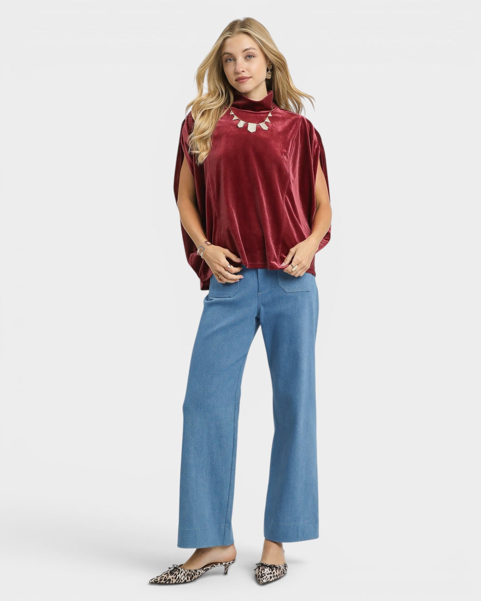 Woman wearing a burgundy top and blue jeans on a white background