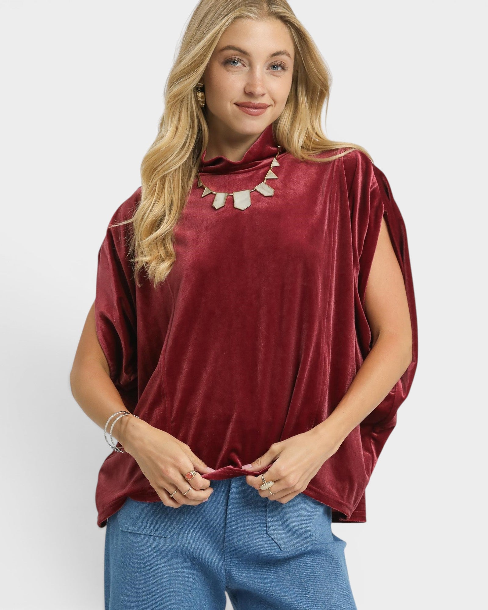 Woman wearing a burgundy top and blue pants on a white background