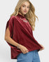 Woman wearing a burgundy top with a high collar and blue pants on a white background