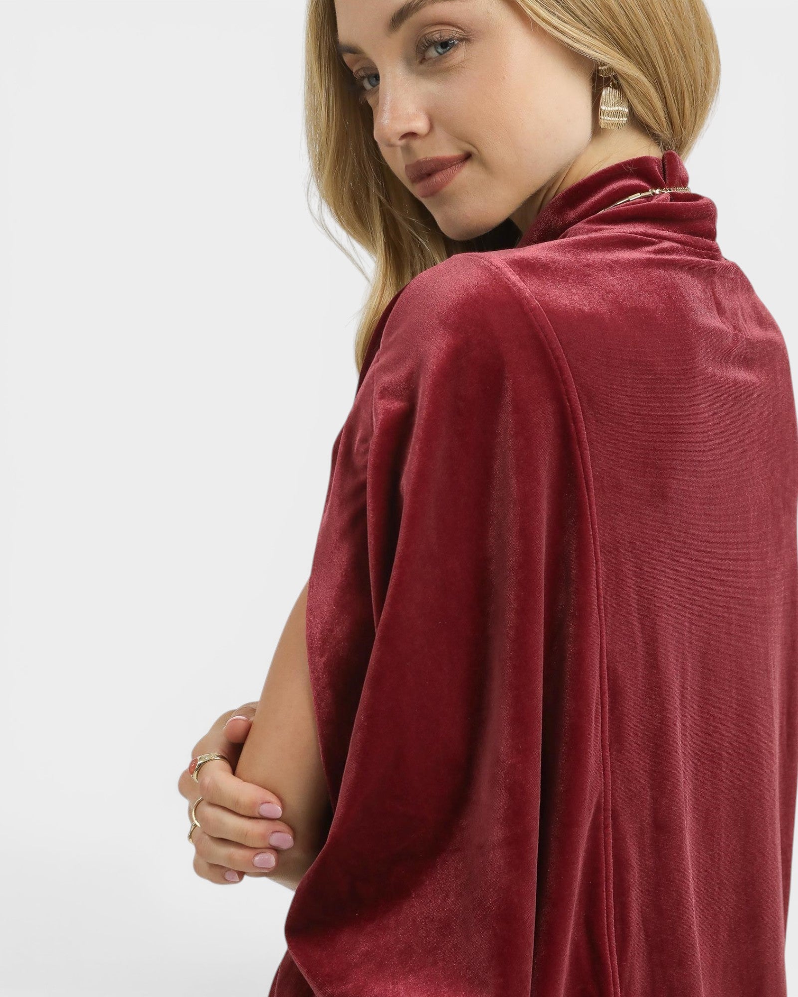 Woman wearing a burgundy poncho against a white background
