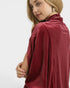 Woman wearing a burgundy poncho against a white background