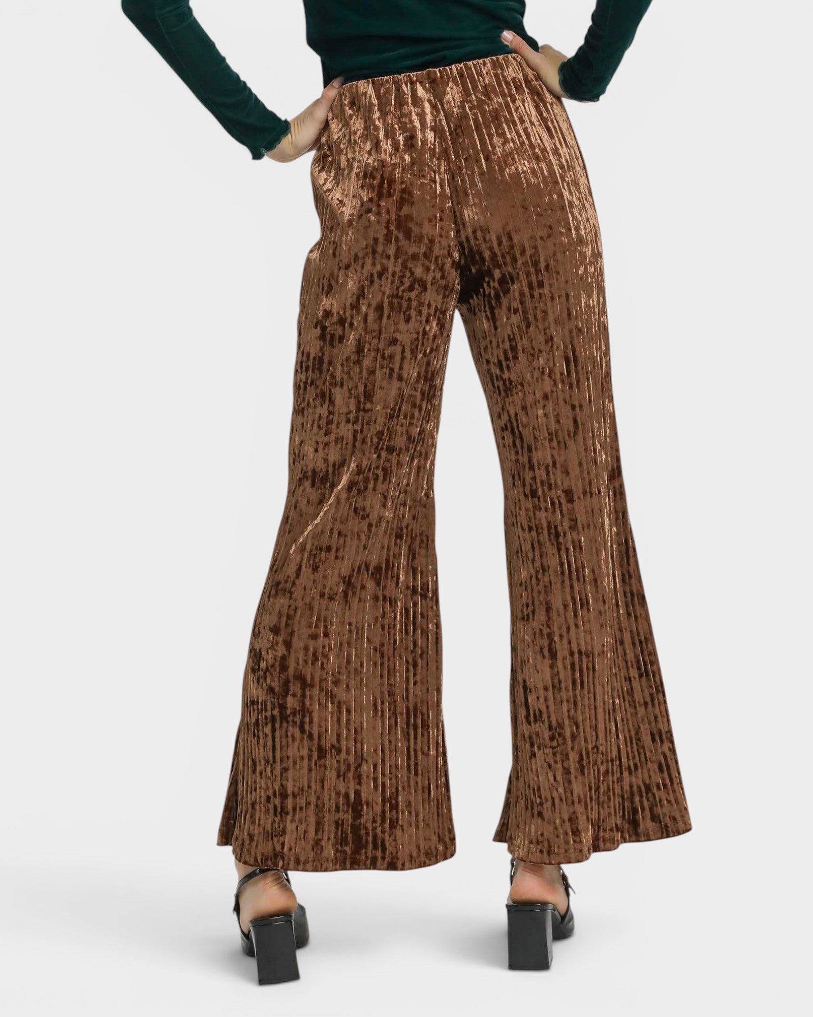 Brown pleated pants worn by a person on a white background