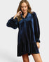 Woman wearing a blue velvet dress on a plain background