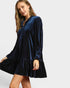 Woman wearing a navy velvet dress on a white background