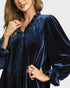 Woman wearing a blue velvet dress with a plain background