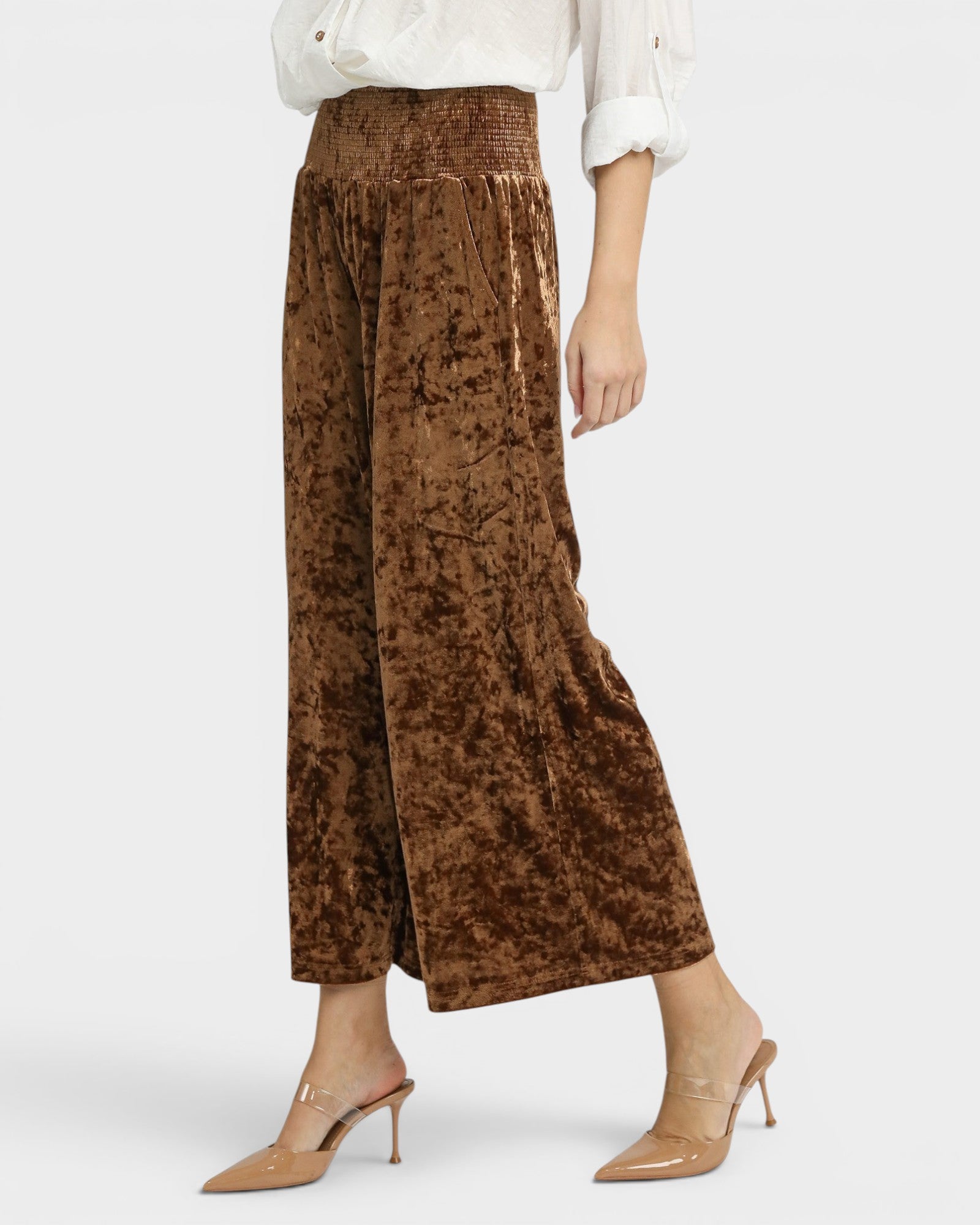 Brown crushed velvet wide-leg pants worn by a person on a white background