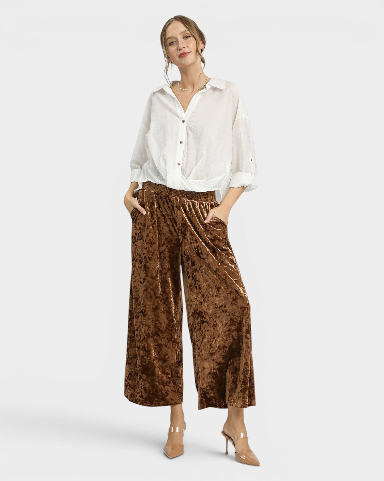 Woman wearing a white blouse and brown patterned pants on a white background