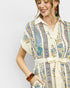Woman wearing a patterned dress with a plain background