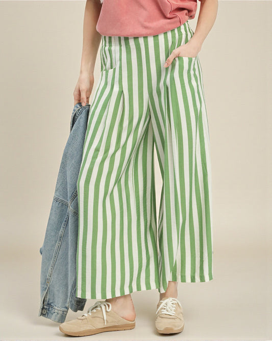 Person wearing green and white striped pants with a denim jacket on a beige background